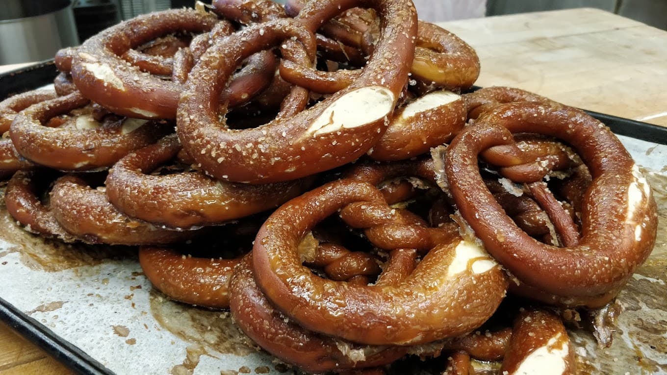 A tray of soft German pretzels cooling on the bakery bench